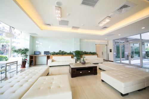 una gran sala de estar con muebles blancos y ventanas grandes. en Sunseed International Villa Hotel, en Chiayi