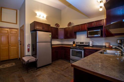 a kitchen with wooden cabinets and a stainless steel refrigerator at Give Something Back Retreat by Revelstoke Vacations in Revelstoke