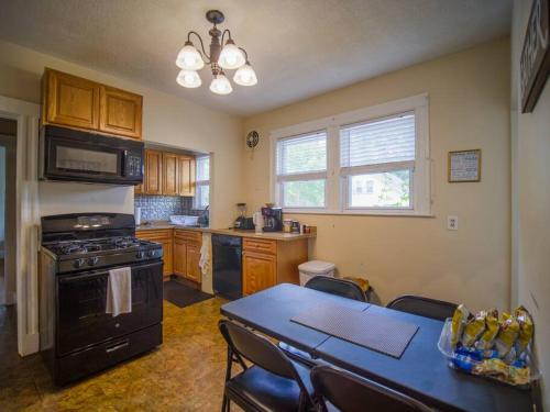 a kitchen with a black stove and a table with chairs at Cozy Large House close to TUFTS/Harvard/MIT 4BR in Medford