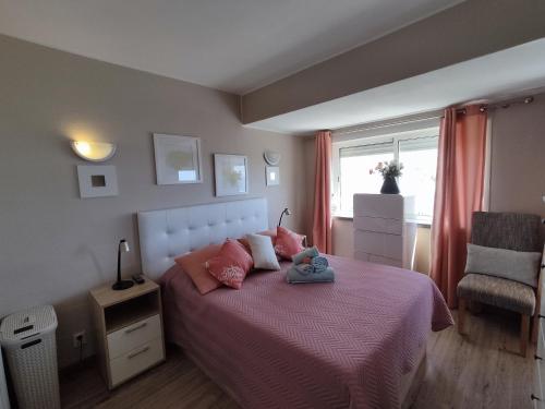 a bedroom with a bed with pink sheets and a chair at 7C Invicta - Casas & Papeis in Armação de Pêra