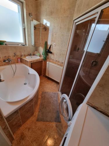 ein Bad mit einer Badewanne, einem Waschbecken und einer Dusche in der Unterkunft Balaton House in Balatonboglár