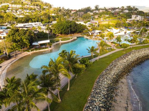 an aerial view of a resort swimming pool with palm trees at Nomads Airlie Beach in Airlie Beach