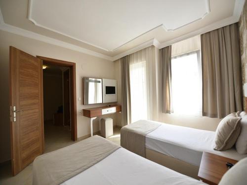 a hotel room with two beds and a television at Nicholas Park Hotel in Fethiye