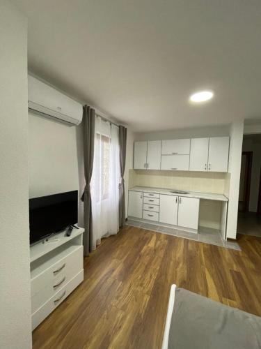 a kitchen with white cabinets and a flat screen tv at Hotel5E in Plav