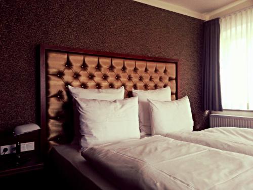 a bedroom with a large bed with white pillows at Hotel Paul Otto in Görlitz