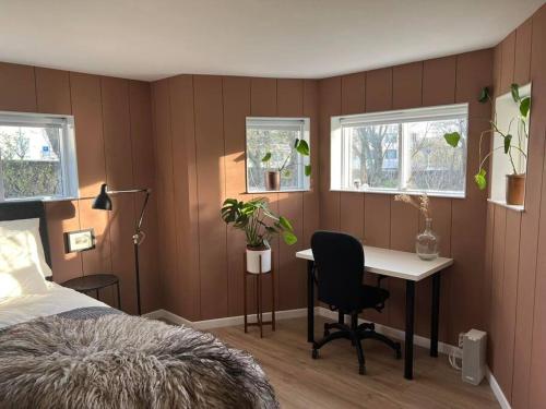a bedroom with a bed and a desk and two windows at New cozy bohemian dowtown Reykjavík apartment in Reykjavík