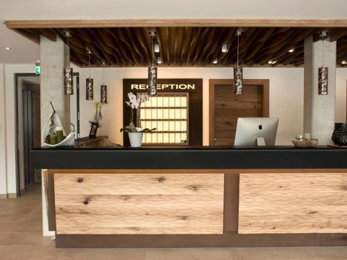 a reception desk with a laptop on top of it at Alpenflair Hotel in Buchloe