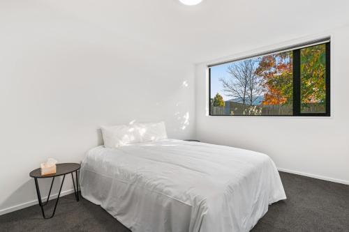 Habitación blanca con cama y ventana en Mountain Escape - Cromwell Downstairs Apartment, en Cromwell