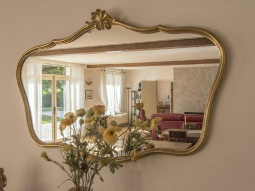 a gold mirror hanging on a wall with a living room at Gîte pour 12 face au château de Thillombois avec jardin, cheminée et équipements PMR - FR-1-585-38 in Thillombois