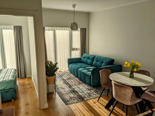 uma sala de estar com um sofá azul e uma mesa em Seaside bungalow Juura at Albatross, Kesterciems with garden, Spa and pool for extra em Ķesterciems