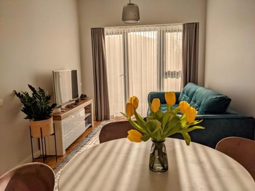 uma sala de estar com uma mesa com um vaso de flores em Seaside bungalow Juura at Albatross, Kesterciems with garden, Spa and pool for extra em Ķesterciems