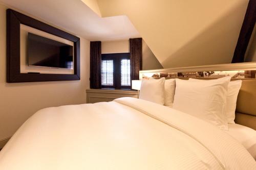 - une chambre avec un grand lit blanc et une fenêtre dans l'établissement 't Goude Hooft, à La Haye