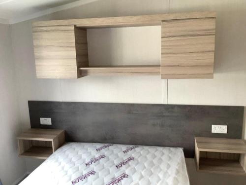 a small bedroom with a bed and two shelves at Caravan on Fantastic site in Dunbar
