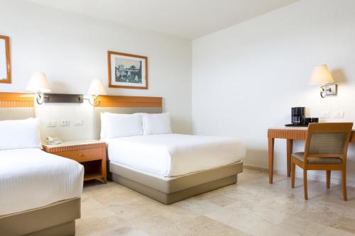 a hotel room with two beds and a desk at Gamma Villahermosa Centro in Villahermosa