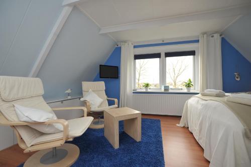 een slaapkamer met 2 stoelen, een bed en een raam bij Aan't Kanaal in Harlingen