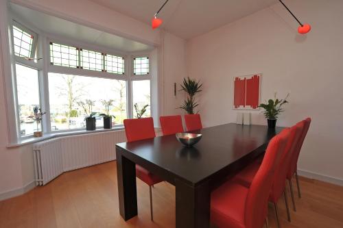 een eetkamer met een zwarte tafel en rode stoelen bij Aan't Kanaal in Harlingen