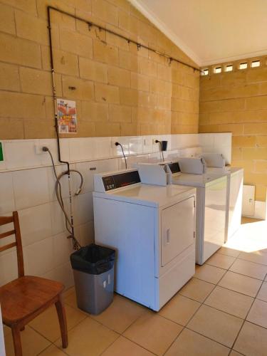 a kitchen with two washers and a table and a chair at Stoney Park Holiday Park in Telegraph Point
