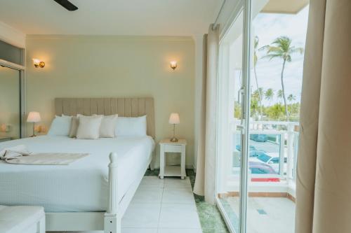 1 dormitorio con 1 cama y balcón en Green Coast Hotel en Punta Cana