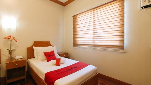 a bedroom with a bed and a window with a red blanket at RedDoorz Premium @ Nick Hotel Gerona Tarlac in Tarlac