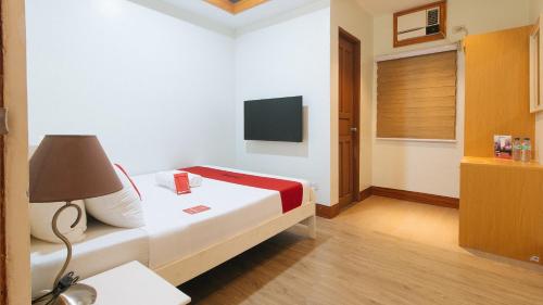 a bedroom with a bed with a lamp and a tv at RedDoorz Premium @ Nick Hotel Gerona Tarlac in Tarlac
