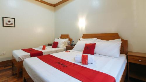 a bedroom with two beds with red and white sheets at RedDoorz Premium @ Nick Hotel Gerona Tarlac in Tarlac