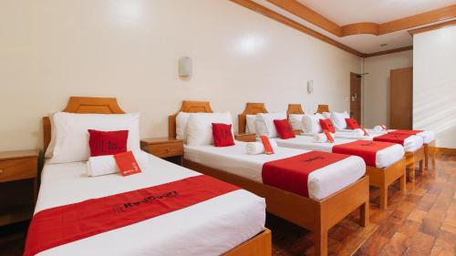 a row of four beds in a room with red accents at RedDoorz Premium @ Nick Hotel Gerona Tarlac in Tarlac