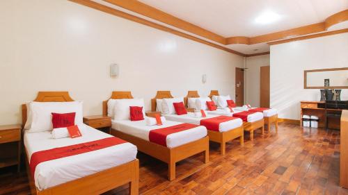 a room with a row of beds with red pillows at RedDoorz Premium @ Nick Hotel Gerona Tarlac in Tarlac
