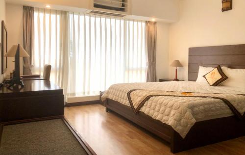 a bedroom with a large bed and a desk and windows at Khách sạn Công Đoàn Quảng Bá in Hanoi