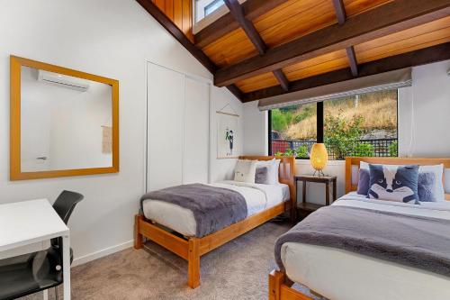 a bedroom with two beds and a mirror at Queenstown Lakefront Dream 4 Bed in Queenstown