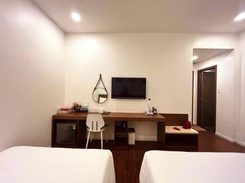 a room with two beds and a desk with a tv at Marina Hotel Phú Yên in Tuy Hoa
