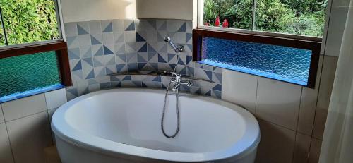 La salle de bains est pourvue d'une baignoire et de 2 fenêtres. dans l'établissement Flor da Vida _ Honeymoon suite - Vale do Capao, à Palmeiras