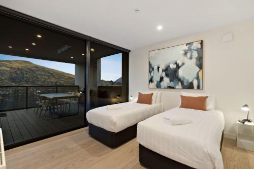 two beds in a room with a balcony at The Bunker Bravo B in Queenstown