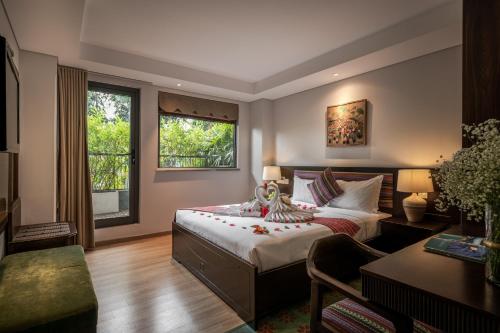 a bedroom with a bed and a desk and two windows at Au Lac Legend Hotel in Ho Chi Minh City