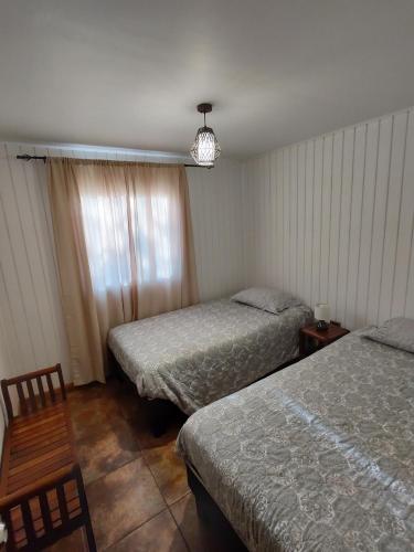 a bedroom with two beds and a chair and a window at "LaEmboscadapuntocl"Casas y departamentos en el huerto in Santa Cruz