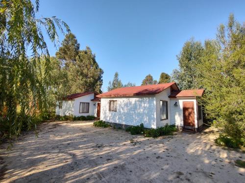 an old house with a red roof on a dirt road at "LaEmboscadapuntocl"Casas y departamentos en el huerto in Santa Cruz