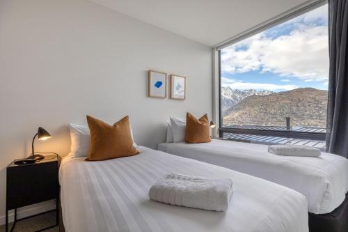 zwei Betten in einem Zimmer mit großem Fenster in der Unterkunft The Rata Luxury Penthouse in Queenstown