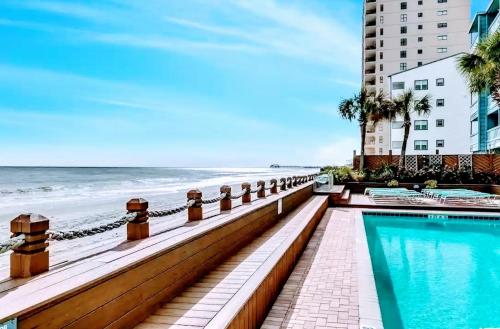 a swimming pool next to a beach next to a building at 0911 Waters Edge Resort condo in Myrtle Beach
