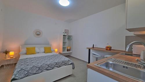 Il comprend une chambre avec un lit et une cuisine avec un évier. dans l'établissement Apartmani Pavlović, à Krk