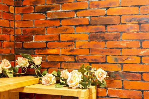 a bunch of roses on a table in front of a brick wall at Anping OAOA Homestay in Anping