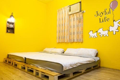 a bed in a room with a yellow wall at Anping OAOA Homestay in Tainan