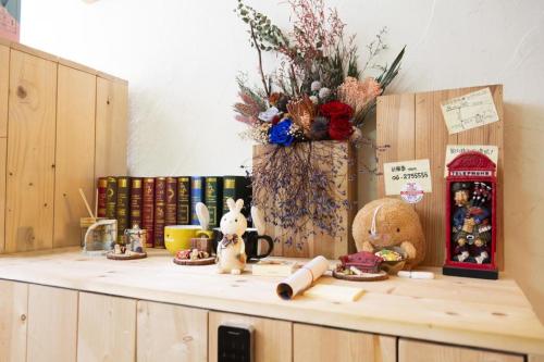 a counter top with a vase of flowers and books at Anping OAOA Homestay in Tainan