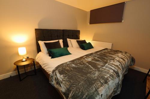 a bedroom with a large bed with green pillows at Declaration Suite in Rhyl