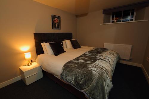 a bedroom with a large bed and a night stand with a lamp at Strength Rooms in Rhyl