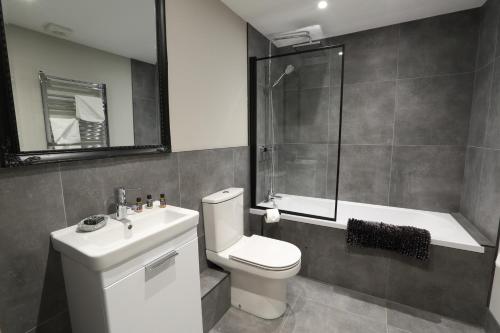 a bathroom with a toilet and a shower and a sink at Strength Rooms in Rhyl