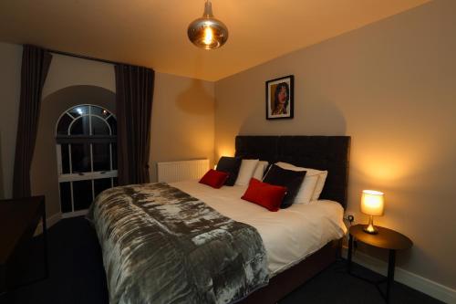 a bedroom with a large bed with red pillows at The Poppy Fields Abode in Rhyl