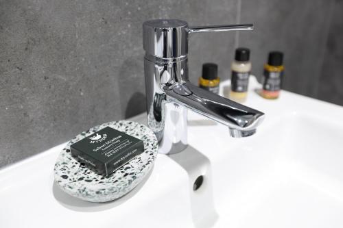 a bathroom sink with a faucet with a book on it at The Poppy Fields Abode in Rhyl