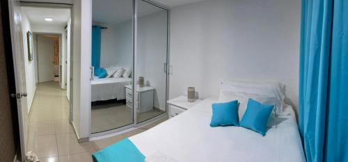 een wit bed met blauwe kussens in een slaapkamer bij Fully Equipped New 3br Apt–dt–2mins To The Beach in Sosúa