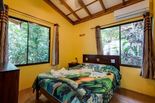 a bedroom with a bed and two large windows at Tropical Beach in Uvita