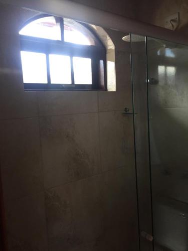 a bathroom with a glass shower with a window at Casa do Trem Suítes in Campos do Jordão