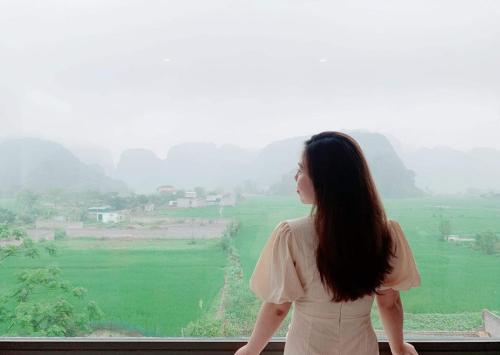 a woman looking out a window at a green field at Cherry homestay in Ninh Binh